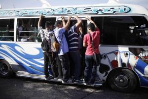 People ride mini bus during a suspension of public transport services in San Salvador